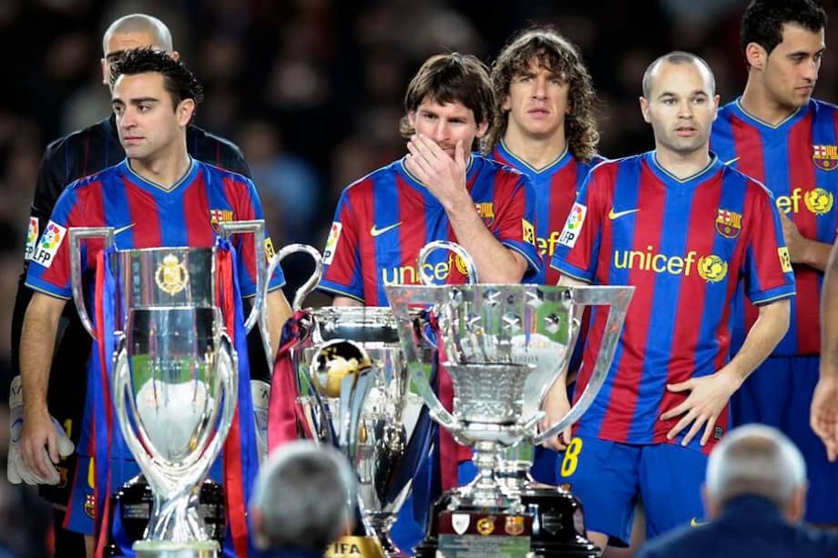 Xavi Hernández (izquierda), Lionel Messi (centro) y Andrés Iniesta (derecha) con los tres trofeos de la temporada 2008-2009.