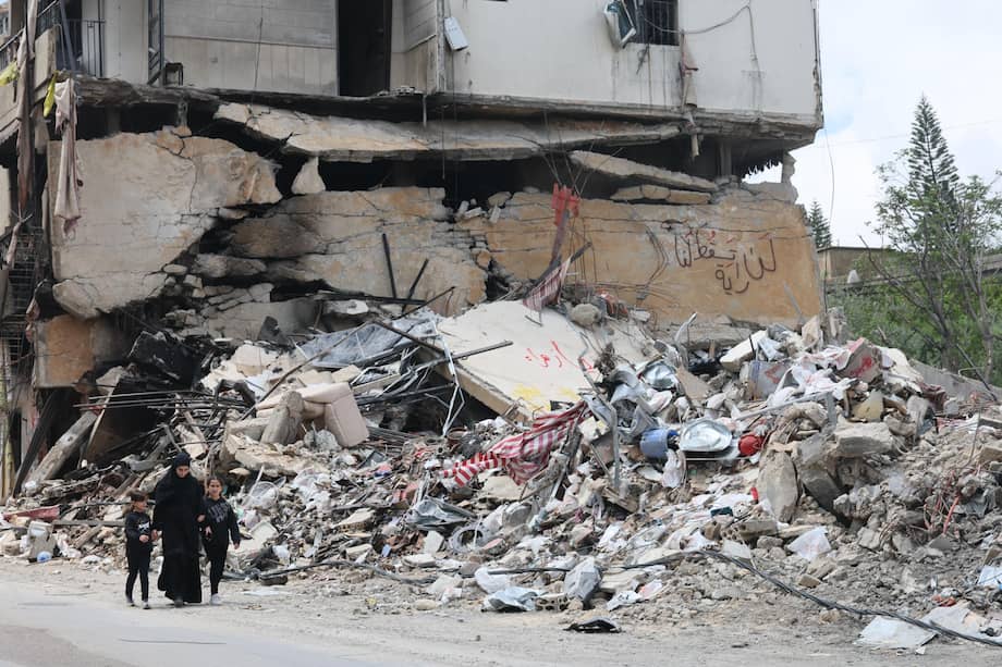 Personas caminan junto a los escombros de un edificio dañado por un ataque aéreo israelí en la aldea de Jibchit, sur de Líbano, el 21 de abril de 2026.