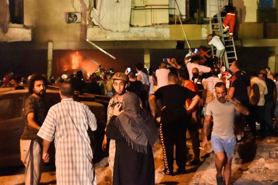 Personas son evacuadas de uno de los edificios afectados por el incendio.