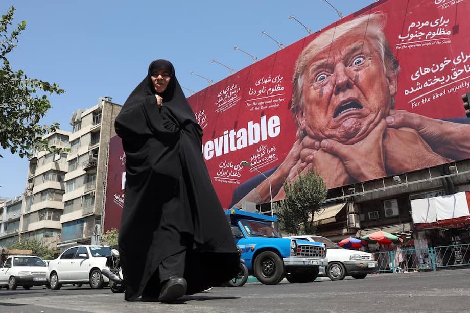 Una mujer camina junto a una valla publicitaria contra Trump en Teherán.