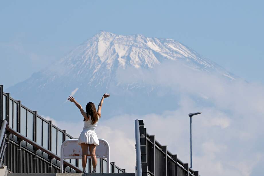 Una turista posa en lo alto de las escaleras que conducen al Fujisan Yumeno Ohashi, o 'Puente del Gran Sueño del Monte Fuji', ya que se ve el Monte Fuji al fondo, en la ciudad de Fuji, prefectura de Shizuoka.