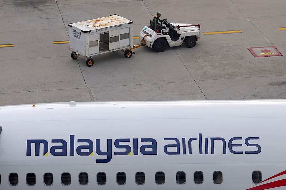 Un trabajador pasa junto a un avión de Malaysia Airlines estacionado en el Aeropuerto Internacional de Kuala Lumpur, en el 11º aniversario de la desaparición del avión de Malaysia Airlines.