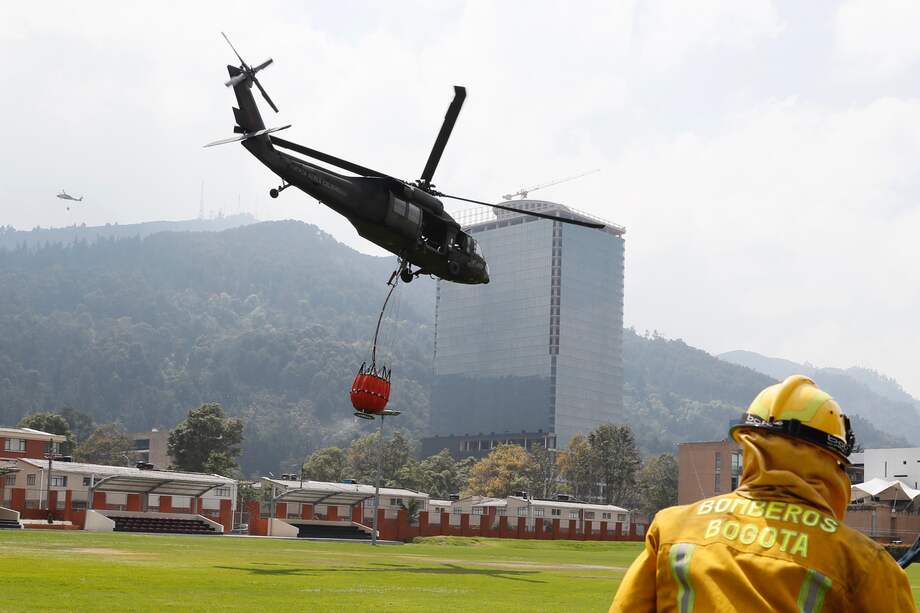 Un helicóptero de la Fuerza Aeroespacial Colombiana (FAC) reabastece hoy con agua el sistema Bambi Bucket para combatir los incendios de los cerros orientales, en Bogotá (Colombia). EFE/ Carlos Ortega