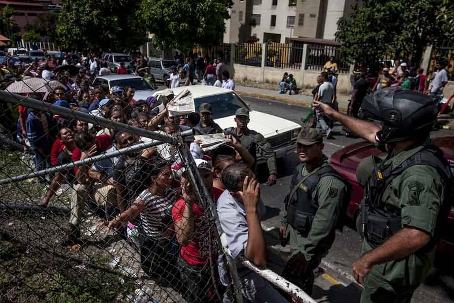 Integrantes de la Guardia Nacional Bolivariana (GNB) hacen presencia junto a una fila frente a un supermercado. / EFE