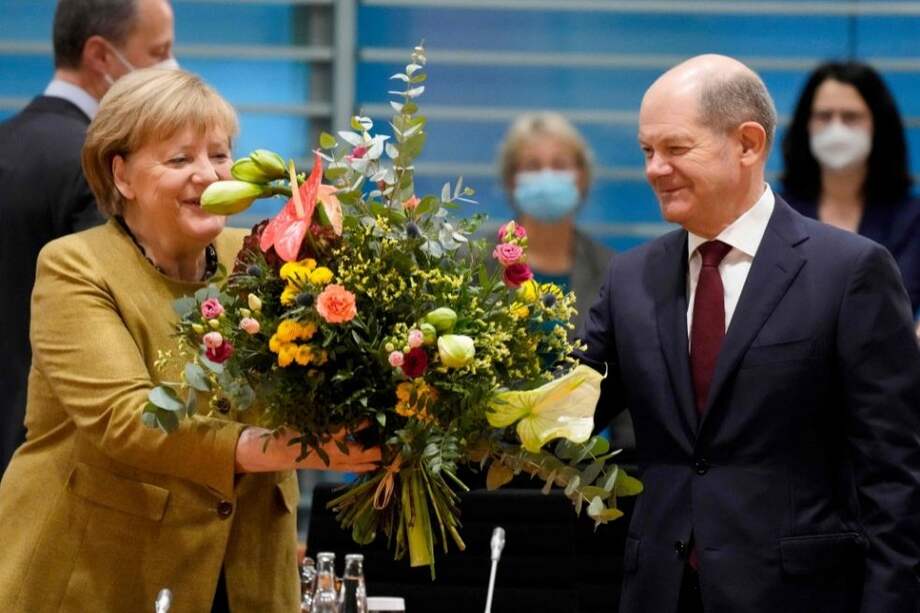 La canciller alemana, Angela Merkel, recibe un ramo de flores del ministro de Finanzas alemán, Olaf Scholz, su sucesor en el cargo.