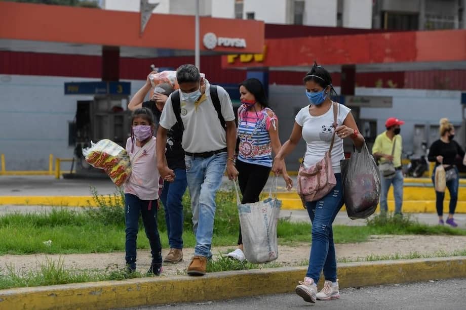 Un grupo de venezolanos usa máscaras faciales mientras lleva bolsas con alimentos en el centro de Caracas.