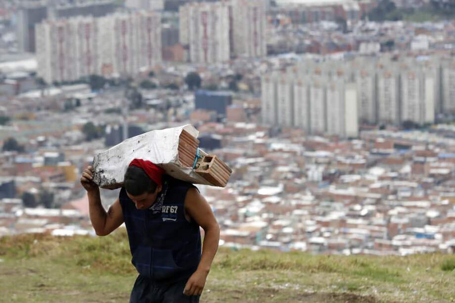 Un hombre carga materiales de construcción en el barrio Altos de la Estancia, en el sur de Bogotá. / EFE
