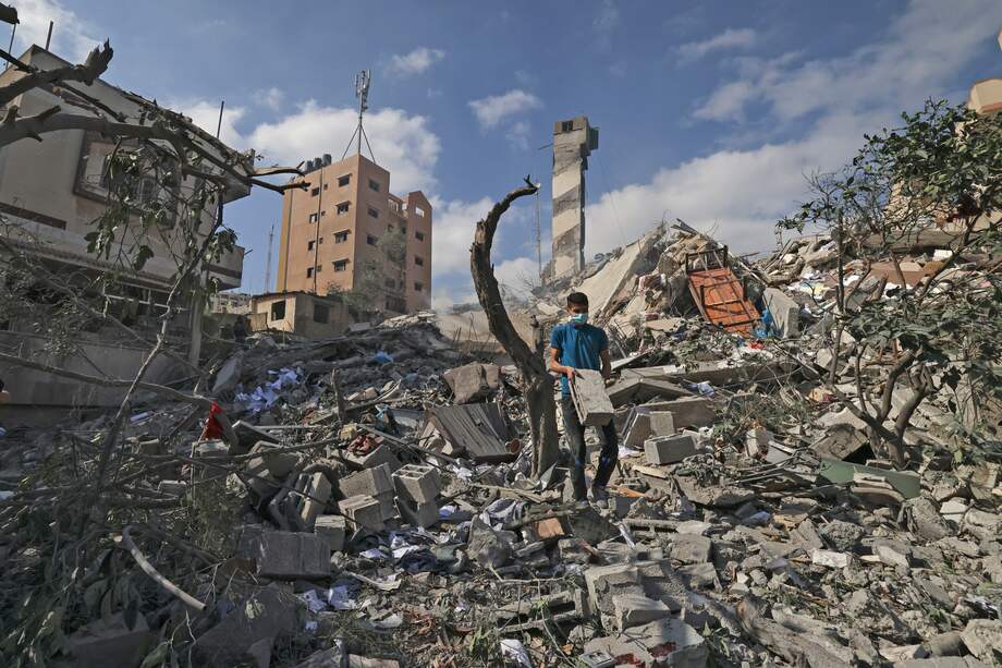 Un joven palestino busca artículos rescatables en medio de los escombros del edificio Kuhail que fue destruido en un ataque aéreo israelí en la mañana en la ciudad de Gaza el 18 de mayo. El edificio tenía una imprenta, accesorios universitarios y una instalación de almacenamiento de libros para institutos educativos en Gaza.