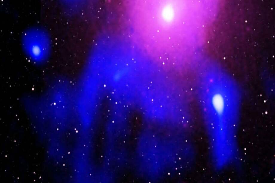 Las ondas de radio (azul) se filtran con un gas emisor de rayos X (púrpura) que envuelve una galaxia masiva (blanca, superior). Las ondas de radio probablemente provienen de electrones de alta velocidad acelerados por una erupción hace mucho tiempo desde un gigantesco agujero negro en el centro de la galaxia. / S. GIACINTUCCI ET AL/NRL, CXC/NASA, XMM-NEWTON/ESA; RADIO: GMRT, TIFR, NCRA; INFRARED: 2MASS/UMASS, IPAC-CALTECH/NASA, NSF