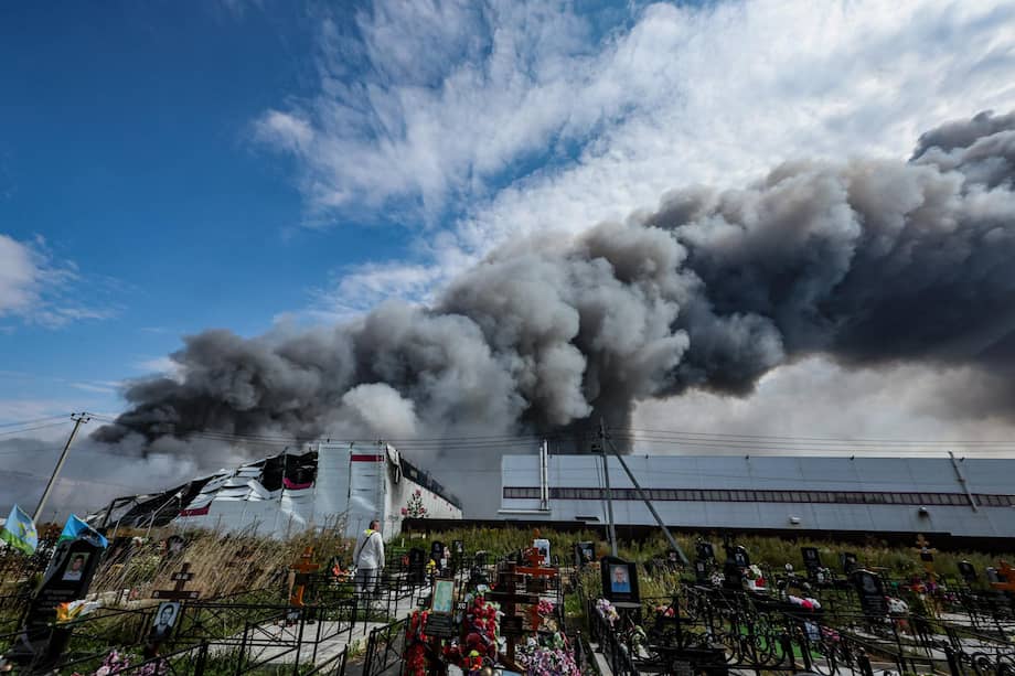 Una persona permanece entre las tumbas de un cementerio mientras el humo se eleva sobre una instalación de Wildberries (al fondo) tras un presunto ataque con drones ucranianos en el parque industrial de Koledino, cerca de Podolsk (región de Moscú, Rusia).