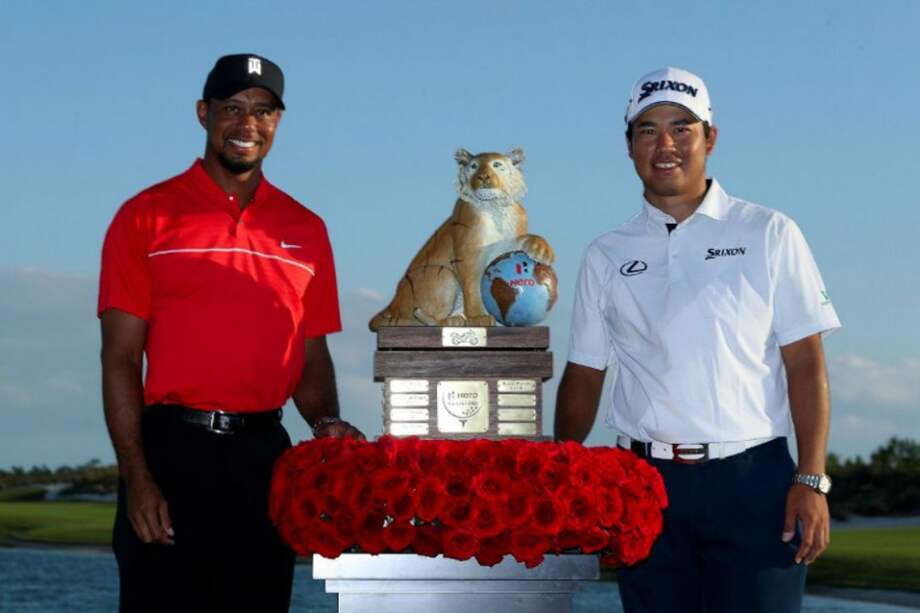 japonés Hideki Matsuyama (d) con el trofeo que ganó este domingo en el Hero World Challenge, junto al legendario estadounidense Tiger Woods. / AFP