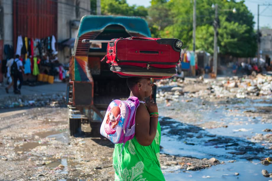 Fotografía de archivo del 10 de diciembre del 2024 de una mujer caminando con sus pertenencias en una calle de Poste Marchand, en Puerto Príncipe (Haití).