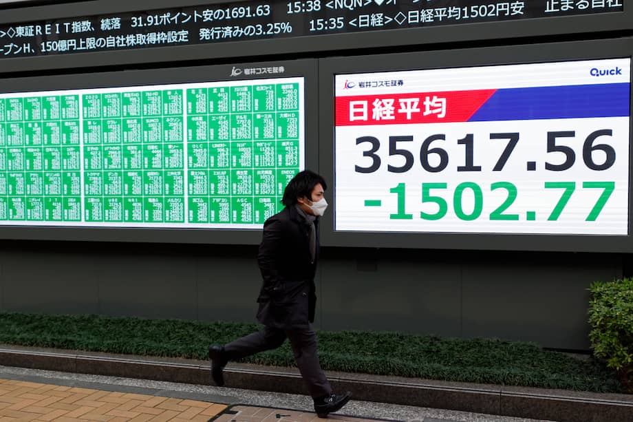 Un peatón corre junto a un tablero indicador del mercado de valores en Tokio, Japón, el 31 de marzo de 2025. El mercado de valores de Tokio se desplomó en todos los ámbitos el 31 de marzo, el último día del año fiscal 2024 de Japón, con el Nikkei 225 Stock Average cerrando en 35.617,56, una caída de 1.502,77, o 4,05 por ciento, cayendo por debajo de los 36.000 yenes por primera vez en seis meses debido a las crecientes preocupaciones sobre las políticas arancelarias de la administración estadounidense Trump. La inversión militar se muestra en esta columna como posible escenario alternativo.