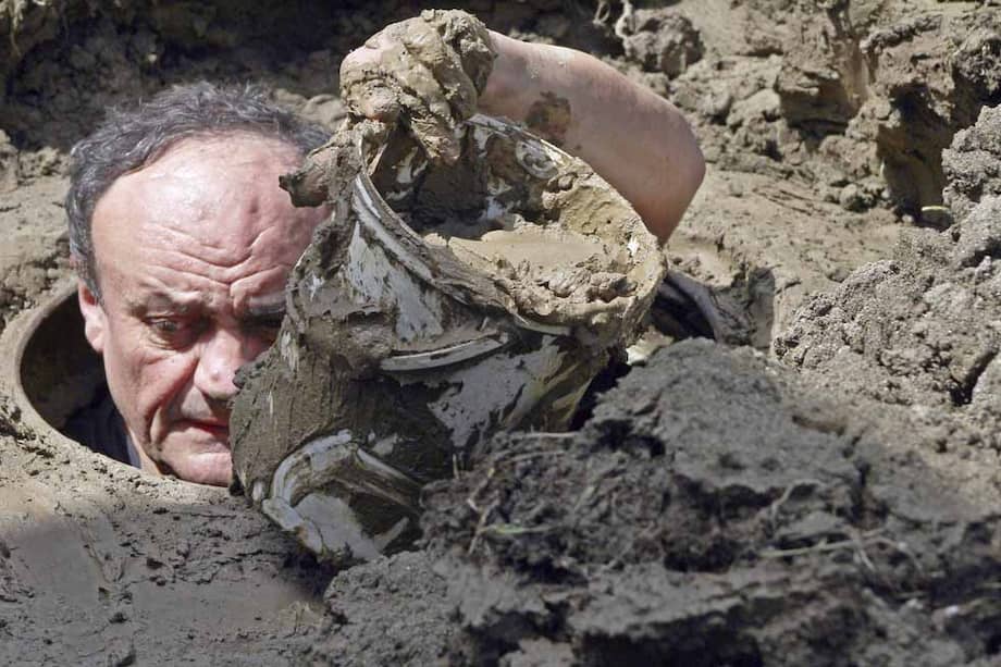 Un hombre desatasca una alcantarilla tras las fuertes inundaciones. / EFE
