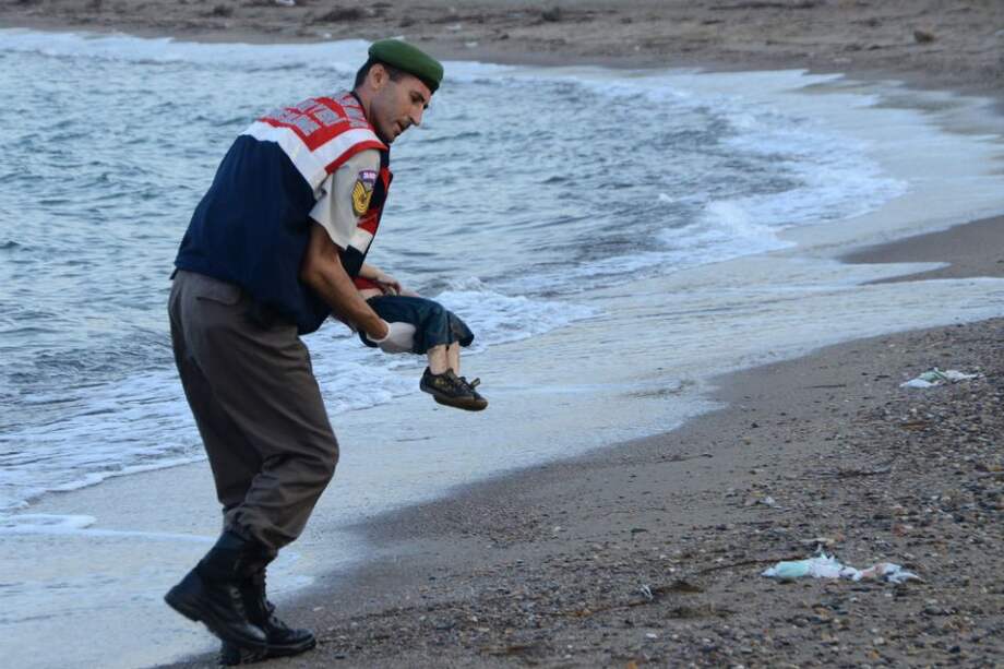 Un soldado turco recoge el cuerpo de Aylan Kurdi, un niño sirio que murió ahogado, en las playas de Turquía. / AFP