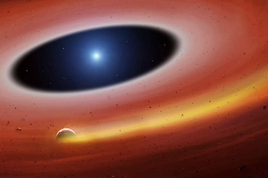 lustración del planetesimal o fragmento planetario (en primer término, dejando a su paso una cola de gas coloreada de amarillo) orbitando la enana blanca que se ve al fondo, en el centro del disco de escombros. / Universidad de Warwick/Mark Garlick