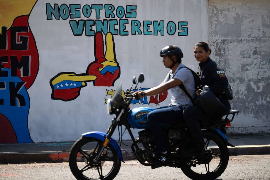 Personas en moto transitan frente a un mural dirigido a Nicolás Maduro. Allí se lee: "Nosotros venceremos".