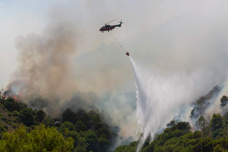 Un helicóptero del servicio de bomberos trabaja en el incendio declarado en la sierra de Mijas, Málaga (España), este sábado.