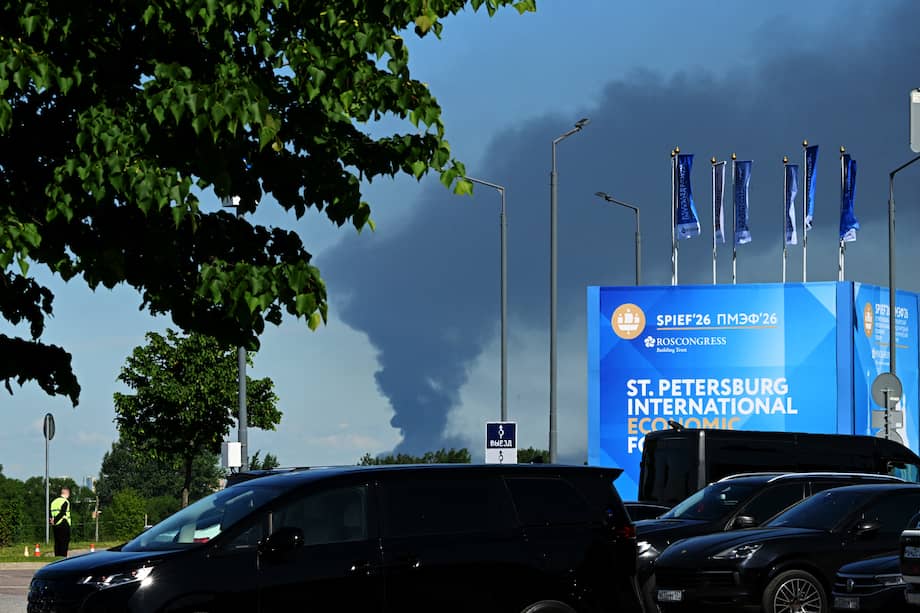 Se observan automóviles estacionados cerca de pancartas con la marca del Foro Económico Internacional de San Petersburgo (SPIEF) en la sede del foro, mientras una columna de humo negro se eleva a lo lejos en la ciudad.