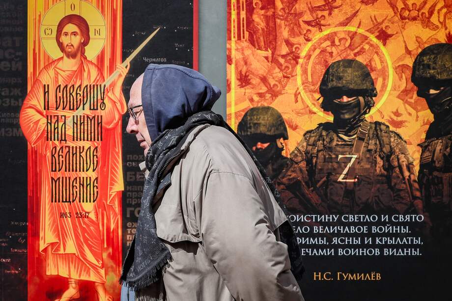 Un hombre pasa junto a una instalación con fotografías de soldados rusos durante una exposición callejera titulada "¡Traemos la paz!" en Moscú, Rusia.