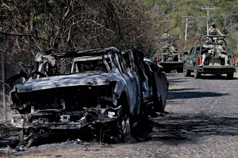 Se observa a miembros del ejército a bordo de camionetas junto a un automóvil incendiado utilizado para bloquear carreteras mientras el capo de la droga mexicano "El Mencho"