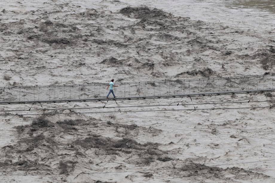 Persona cruza un puente sobre el desbordado río Trishuli en Dhading, Nepal, tras las devastadoras inundaciones que dejan más de 700 muertos.