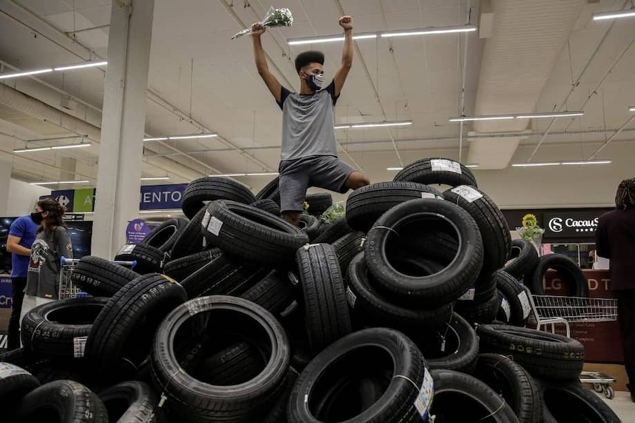 Un hombre arriba de una montaña de neumáticos puestos por manifestantes en un supermercado Carrefour del barrio de Barra da Tijuca, para impedir las ventas durante una protesta contra el asesinato de Joao Silveira, en Río de Janeiro (Brasil).
