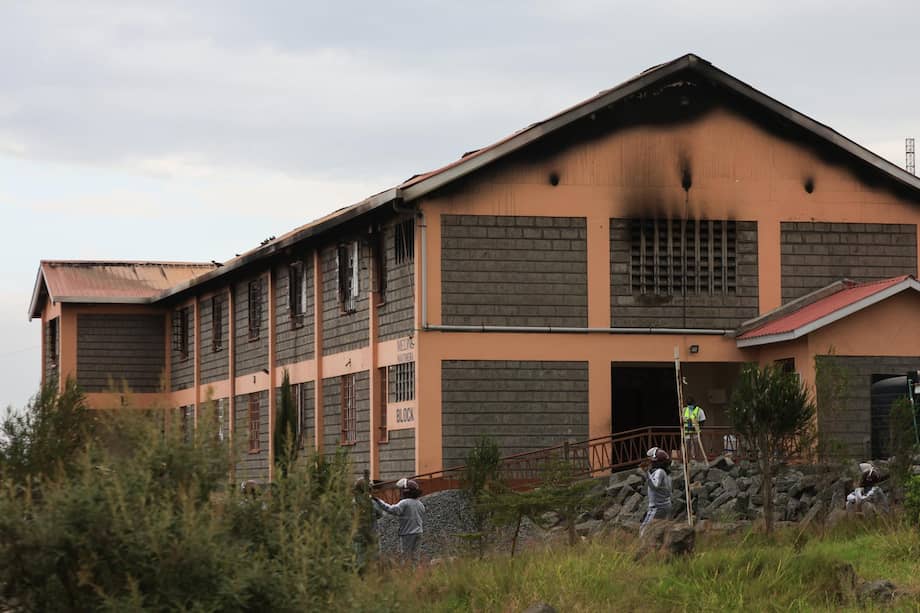 Varias personas permanecen cerca del edificio de la residencia estudiantil de la Academia Femenina Utumishi luego del incendio.