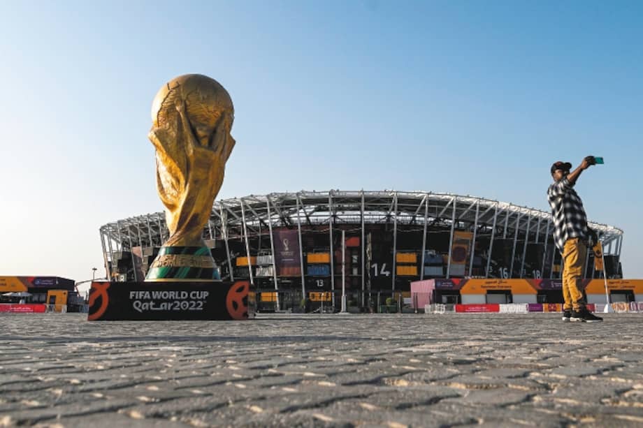 Un hombre se toma una foto frente a una réplica del trofeo de la Copa del Mundo, al frente del Estadio 974 en Doha, capital de Catar.
