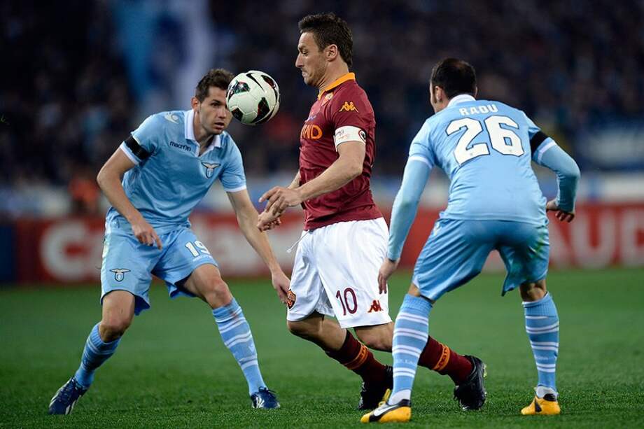 Francesco Totti de la Roma controla el balón en medio de Senad Lilic y Stefan Radu de la Lazio. / AFP