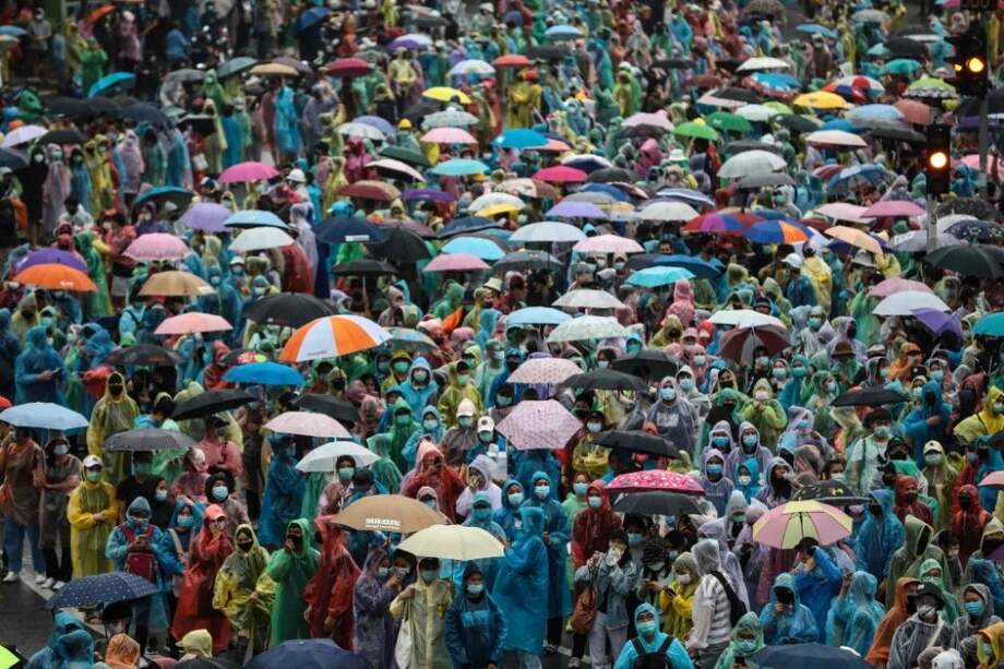 Los manifestantes a favor de la democracia se protegen de la lluvia usando ponchos y paraguas durante una protesta contra el gobierno en el Monumento a la Victoria en Bangkok.