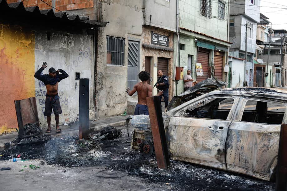 Un integrante de la Policía de Río de Janeiro custodia a dos personas durante un operativo el 28 de octubre de 2025, en Río de Janeiro (Brasil).