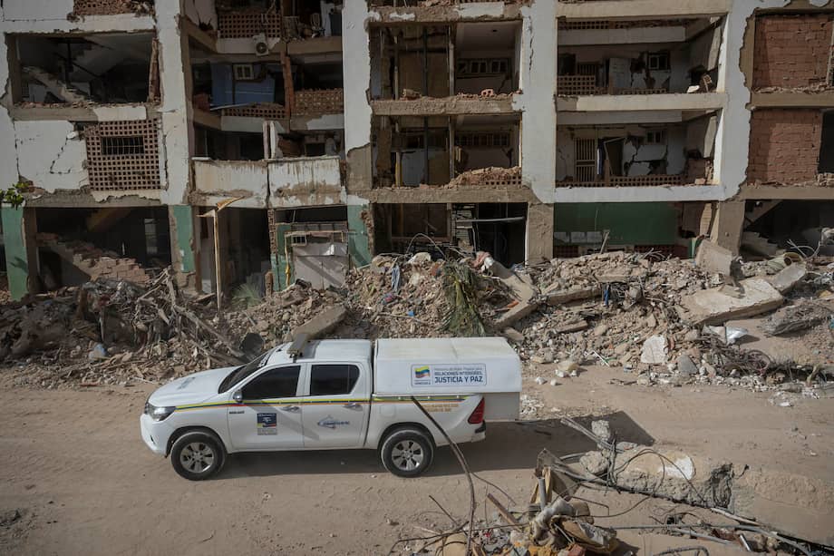 Fotografía que muestra un vehículo del Servicio Nacional de Medicina Legal y Ciencias Forenses transitando frente a edificios destruidos por terremotos este viernes, en Caraballeda (Venezuela).