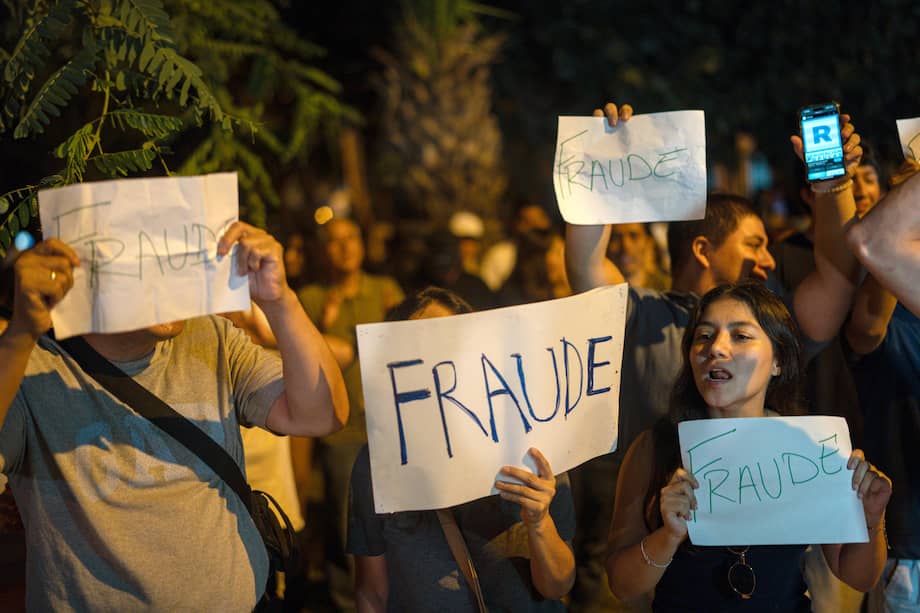 Personas sostienen carteles durante una manifestación por la extensión de las votación y encontra del fraude electoral este domingo, frente al Jurado Nacional de Elecciones (JNE).