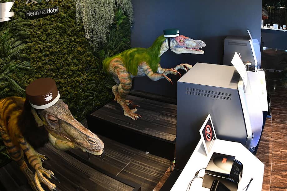 Un par de dinosaurios robot con sombreros de botones dan la bienvenida a los huéspedes desde la recepción del Hotel Henn-na. / AFP PHOTO / Kazuhiro NOGI