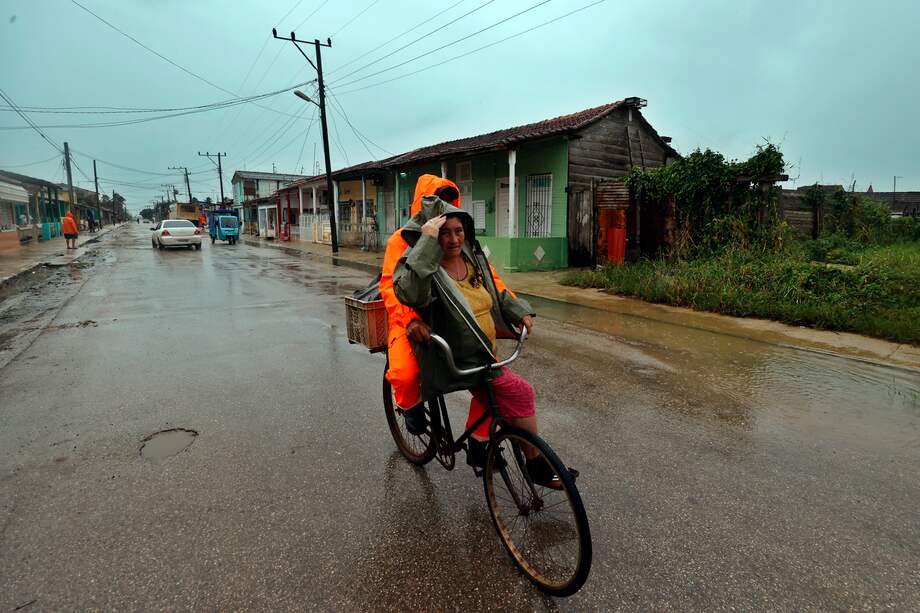 Dos personas se movilizan en bicicleta bajo la lluvia, este miércoles en Surgidero de Batabanó, un puerto pesquero en la provincia occidental de Mayabeque, a unos 50 kilómetros al sur de La Habana (Cuba).
