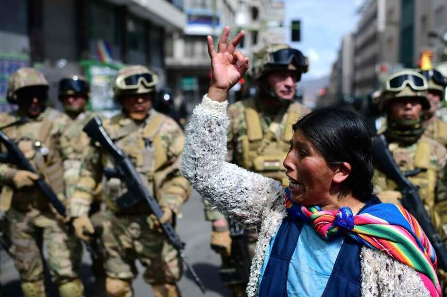 Una mujer indígena boliviana, partidaria del ex presidente boliviano Evo Morales, hace un gesto frente a los soldados durante una protesta contra el gobierno interino en La Paz el 15 de noviembre de 2019. / AFP
