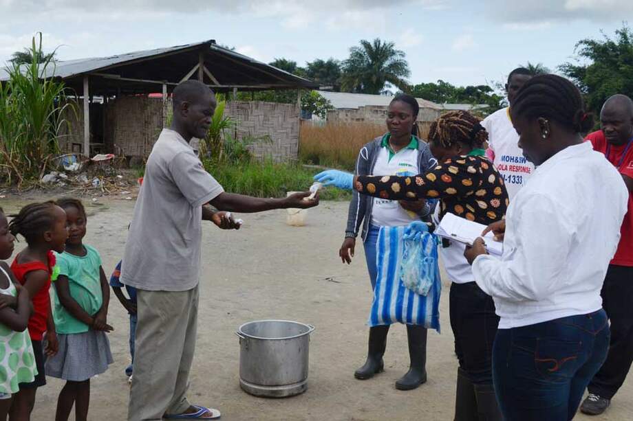 Miembros de la ONG U Foundation prestan atención a familias en cuarentena por el ébola en Monrovia, capital de Liberia. / AFP