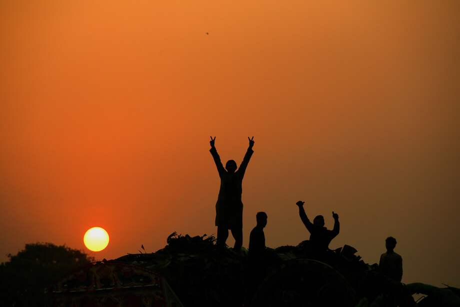 La gente hace un gesto de celebración mientras el sol se pone por última vez en 2023 en Peshawar, Pakistán, el 31 de diciembre de 2023.