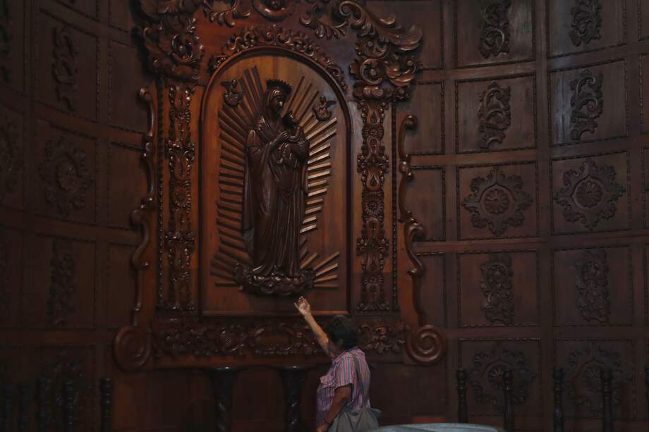 Mujer rezando en una iglesia católica en Cali.