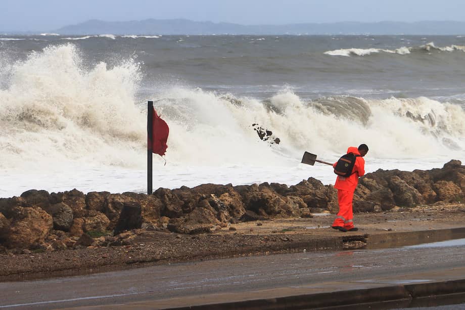 Un trabajador limpia un sector de la avenida Santander inundado por el mar en Cartagena.