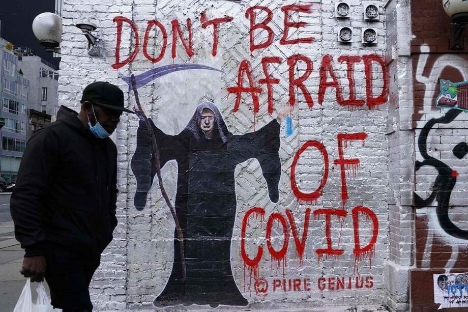 Un hombre pasa junto a un mural dibujado por el artista "Pure Genius" que representa al presidente de los Estados Unidos, Donald Trump, como la Parca.