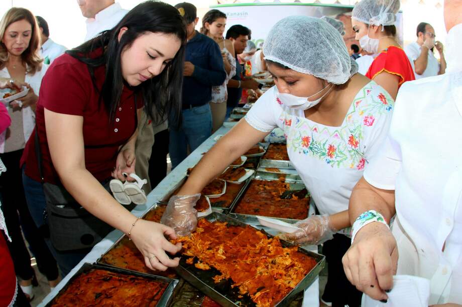 Habitantes de Yucatán reciben un pedazo del tamal gigante cocinado este sábado. / EFE