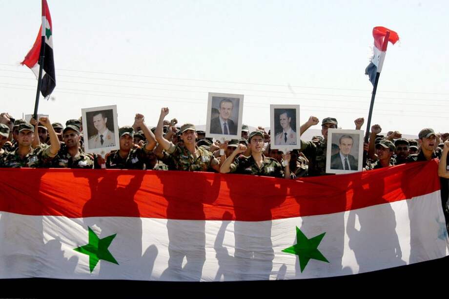 Soldados sirios con banderas de su país y retratos del presidente Bashar Al Assad durante una ceremonia para conmemorar el 67 Día del Ejército. Foto: EFE