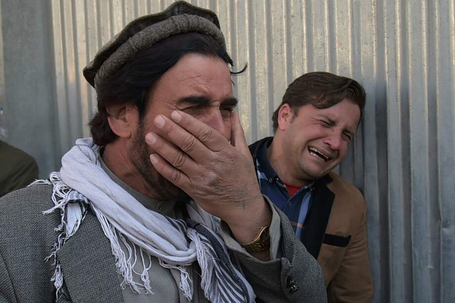 Dos afganos lloran por sus familiares en la entrada del hospital Sardar Daud Khan en Kabul. / AFP