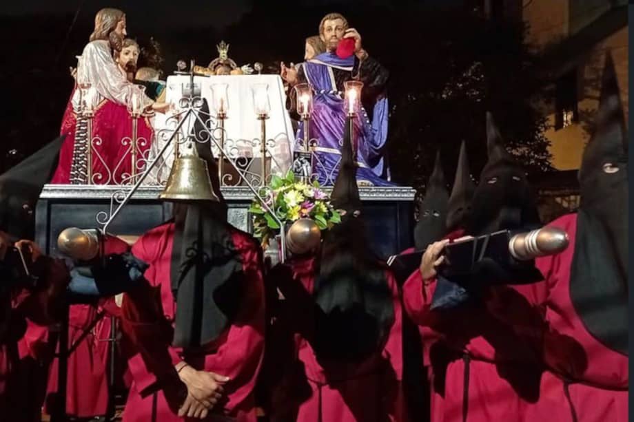 Cargueros de la Cofradía Pasionista de la Parroquia El Calvario, con túnicas rojas y capirotes negros en la procesión de prendimiento.