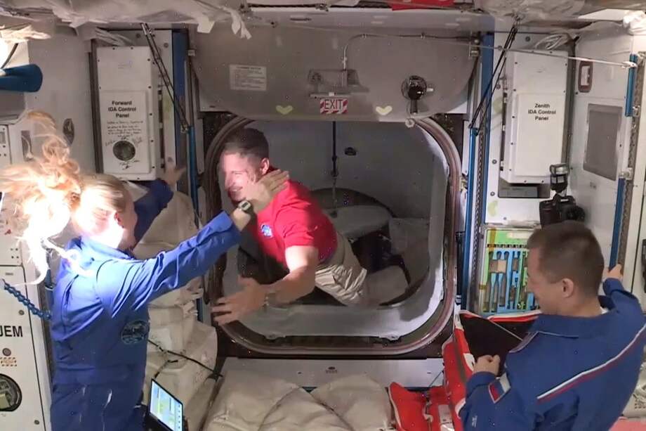 Miembros de la tripulación de la nave espacial SpaceX Crew Dragon (de rojo) son recibidos en la Estación Espacial Internacional.