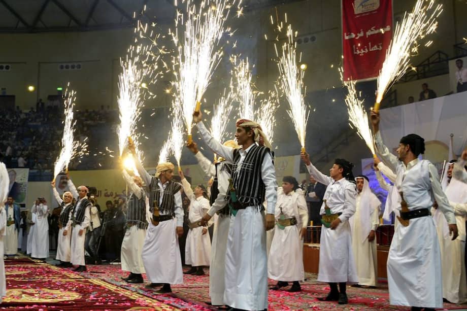 Varios hombres sostienen fuegos artificiales durante la boda masiva celebrada en Saná, Yemen./