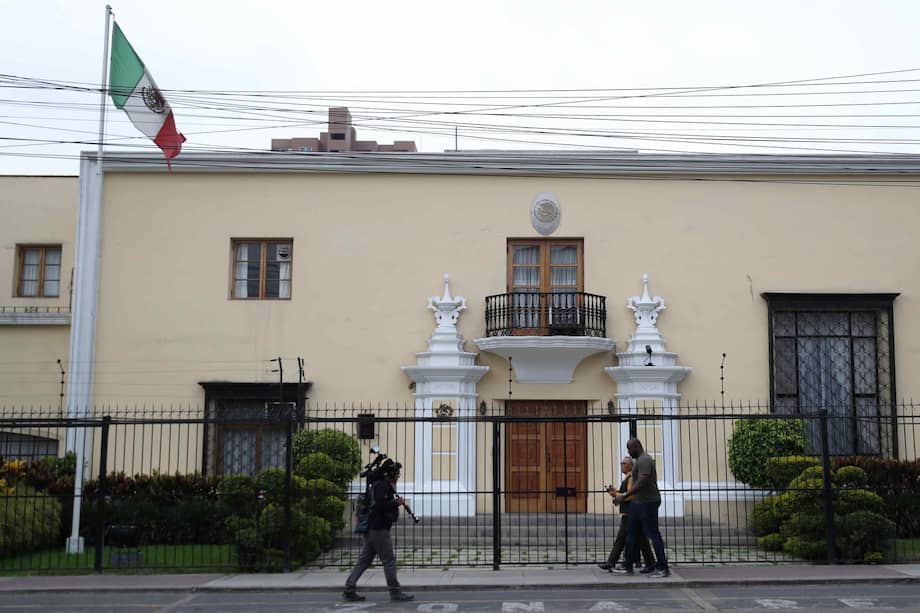 Personas caminan frente a la Embajada de México en Lima, Perú, donde está refugiada una exministra de Pedro Castillo.