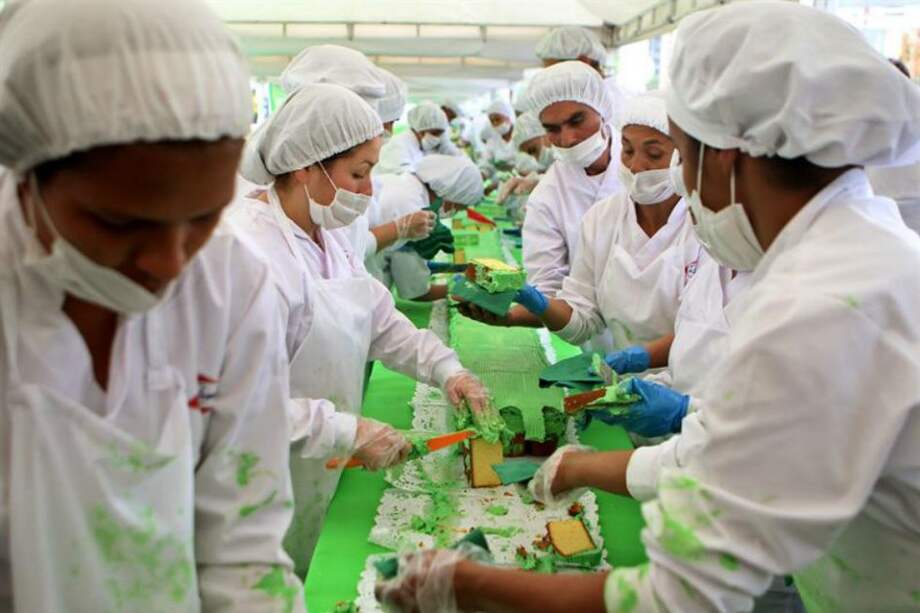 Un grupo de personas corta un pastel de 606 metros con el cual se impuso un nuevo Guinnes Record en Bogotá. La torta se realizó con más de 5.000 kilos de ponqué, 2.000 kilos de crema para decorar, 2.000 kilos de harina de trigo, cerca de 2.000 kilos de azúcar y margarina, más de 30.000 huevos, y la participación de más de 180 personas.